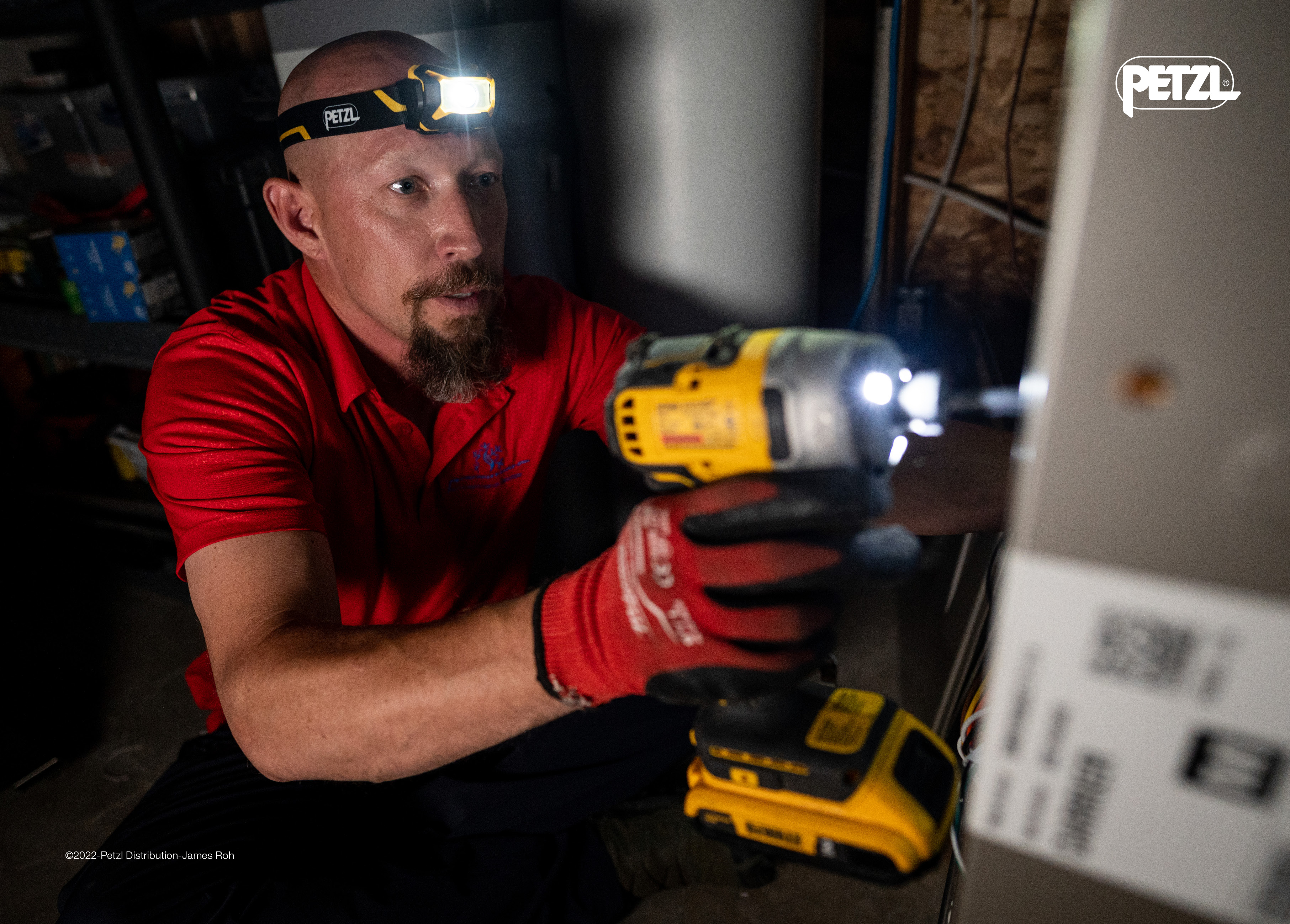 Mies käyttää porakonetta sekä otsalamppua, joka valaisee työalueen tehokkaasti hämärässä ympäristössä.